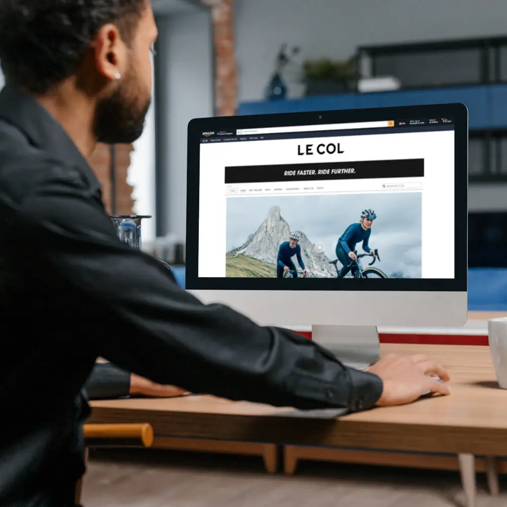 man on desktop computer that shows Le Col Amazon store